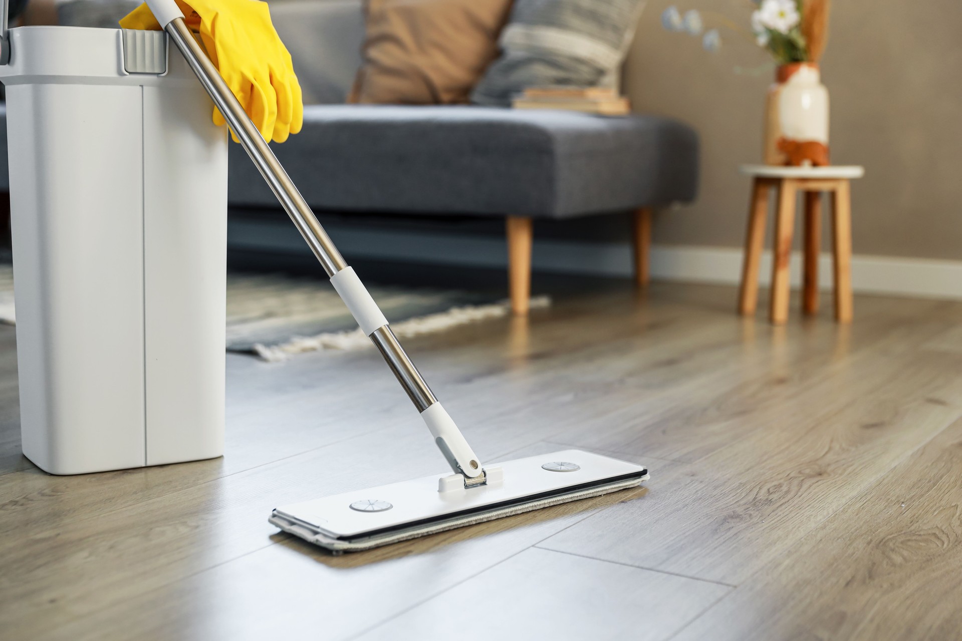 Cleaning supplies: mop, gloves, bucket with wringer on wooden laminate floor